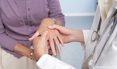 the doctor examines the joints of the hand with arthrosis and arthritis